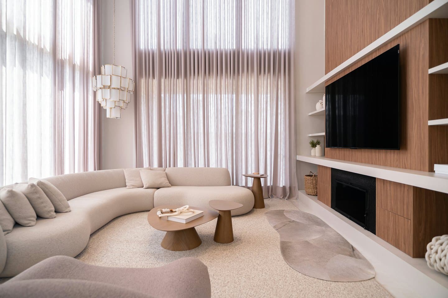 Modern living room with curved beige sofa and fireplace.